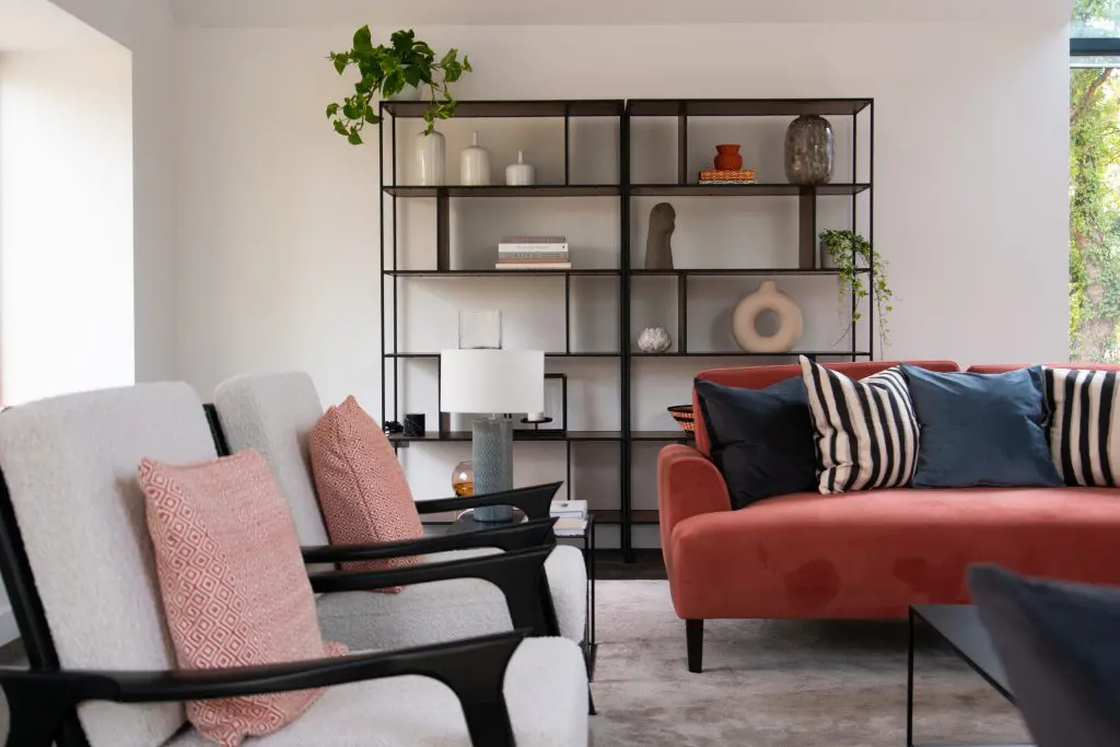 Interior shot of living room with chairs, sofa and open shelves styled by Alix Stoney of Amberley Studio.